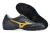 Black and gold Mizuno Monarcida soccer shoes with a textured sole, positioned to show both sides.