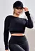 Top cropped manga longa de tela Dry Fit preto, modelo feminino usando um boné preto.