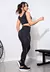 Modelo vestindo conjunto fitness preto, composto por cropped e calça legging, posando em ambiente de academia.