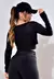 Modelo usando um top cropped manga longa de tela dry fit preto, exibindo a parte de trás da peça em um ambiente iluminado.