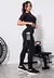 Modelo usando conjunto fitness cropped preto e calça legging com bolso tela, em ambiente de treino.