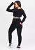Modelo usando um conjunto fitness preto, composto por calça legging e cropped de telinha, visto de lado.