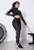 Conjunto fitness composto por calça legging com elástico e tela, e cropped de manga longa com gola alta, em cor preta.