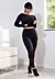 Modelo vestindo conjunto cropped preto com calça legging, destacando detalhes em tela, em ambiente moderno.
