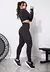 Modelo usando conjunto fitness preto com cropped de manga longa e calça legging, em ambiente de treino.