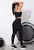 Modelo usando conjunto de legging e top preto com detalhes em transparência, em ambiente fitness.