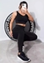 Modelo usando conjunto de calça legging e cropped preto, posando em um ambiente fitness.