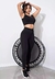 Modelo vestindo um conjunto de calça legging e cropped na cor preta, posando ao lado de um mini trampolim.