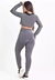 Modelo usando conjunto fitness cinza com calça legging e cropped de manga longa, visto de costas.