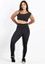 Modelo usando um conjunto de calça legging preta com cropped preto, destacando a listra branca na alça da blusa.