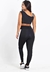 Modelo de calça legging preta com listra branca, vista traseira, acompanhada de cropped preto.