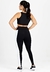 Modelo vista de costas usando um conjunto de cropped preto e calça legging com detalhes em verde e branco.