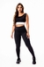 Modelo usando um conjunto fitness feminino composto por calça legging preta com detalhe em vivo branco e cropped regata.