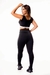 Modelo usando calça legging preta com detalhe em vivo branco e cropped regata, ideal para academia.