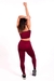 Modelo usando conjunto fitness marsala com cropped e calça legging de cintura alta, vista traseira.