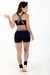 Modelo usando conjunto fitness preto com cropped e short, visto de costas.