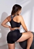 Modelo usando um conjunto fitness preto com cropped e short, destacando a parte de trás do look.