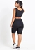 Conjunto fitness feminino na cor preta, composto por cropped e bermuda, visto de costas.