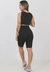 Mulher usando um conjunto fitness feminino preto com cropped e bermuda, vista de costas.