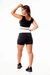 Modelo feminina usando conjunto fitness preto e branco, com cropped regata e short cintura alta, vista de costas.