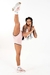 Modelo exibindo um conjunto fitness rosa, composto por um cropped com alças duplas e um short cintura alta, em uma pose de exercício.