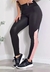 Calça legging fitness preta com detalhes em rosa, modelo ajustado, usada por uma mulher em ambiente moderno.