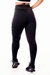 Calça legging fitness preta com detalhe lateral em branco, vista traseira, usada por uma modelo em ambiente neutro.