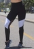 Calça legging cintura alta assimétrica com detalhes em branco e tulê, modelo preto, em ambiente urbano.