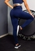 Calça legging marinho com cintura alta, usada por uma modelo em ambiente de treino, destacando o ajuste e o conforto da peça.