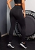 Calça legging preta com bolso e elástico na cintura, vista traseira, em ambiente de treino.