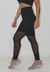 Calça transparente legging fitness preta com detalhe em tule, usada por uma modelo em pé.