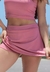 Modelo usando short saia fitness na cor rosé, ideal para atividades esportivas.