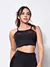 Top cropped fitness preto com detalhe transparente, modelo feminino, em fundo neutro.