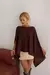 Mulher usando blusa estilo boho marrom com detalhes de textura, combinada com saia curta bege e botas de cano alto em couro.