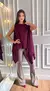 Mulher usando blusa estilo boho vinho com detalhes de textura, combinada com saia curta bege e botas de cano alto em couro.