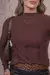 Modelo usando blusa de tricot  na cor marrom, com saia de couro preta e cinto de estampa de leopardo.