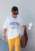 Modelo usando uma T-Shirt off white, oversize, com estampa peaches.