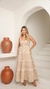 Vestido longo em tom bege, com detalhes dourado, com renda e franjas, modelagem leve e fluida.