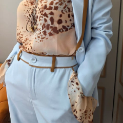 Calça feminina de alfaiataria azul claro com viés caramelo e forro interno. Elegante, sofisticada e perfeita para looks de trabalho ou ocasiões especiais.