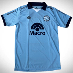 Camiseta titular de Belgrano para la temporada 2024/25, color celeste con detalles en azul marino y logotipo de Umbro.