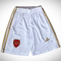 Shorts de fútbol blancos con detalles dorados y escudo del Arsenal en la parte frontal.