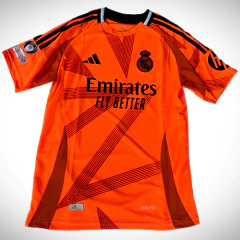 Camiseta suplente del Real Madrid 2024/25 en color naranja, con diseño gráfico y logo de Adidas.