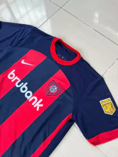 Camiseta de fútbol Nike de San Lorenzo, diseño titular 2024/25 con franjas rojas y azules.