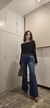 Mujer usando el Jean Clásico Wide Leg de la marca Kinan Kahel. La mujer esta usando un look de sweater bardot negro, stilettos marrones, un Bagkin estilo Hermes de Kinan Kahel y Joyería en Oro de la misma marca.