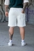 Vista trasera de un hombre usando short blanco Rustico con bolsillo en la parte trasera y zapatillas blancas, en un entorno urbano con grafitis