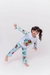 Pijama infantil de manga longa e calça com estampa da Moana, usada por menina sorridente em fundo claro