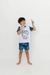 Criança sorrindo vestindo pijama infantil de manga curta com estampa de dragão e shorts coloridos.