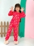 Menina sorridente vestindo pijama básico infantil vermelho com estampas de lua, estrelas e nuvens