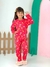 Menina sorridente vestindo pijama básico infantil vermelho com estampas de lua, estrelas e nuvens