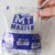 Pacote de pregos telheiro da marca Master, com um prego sendo segurado à mão.